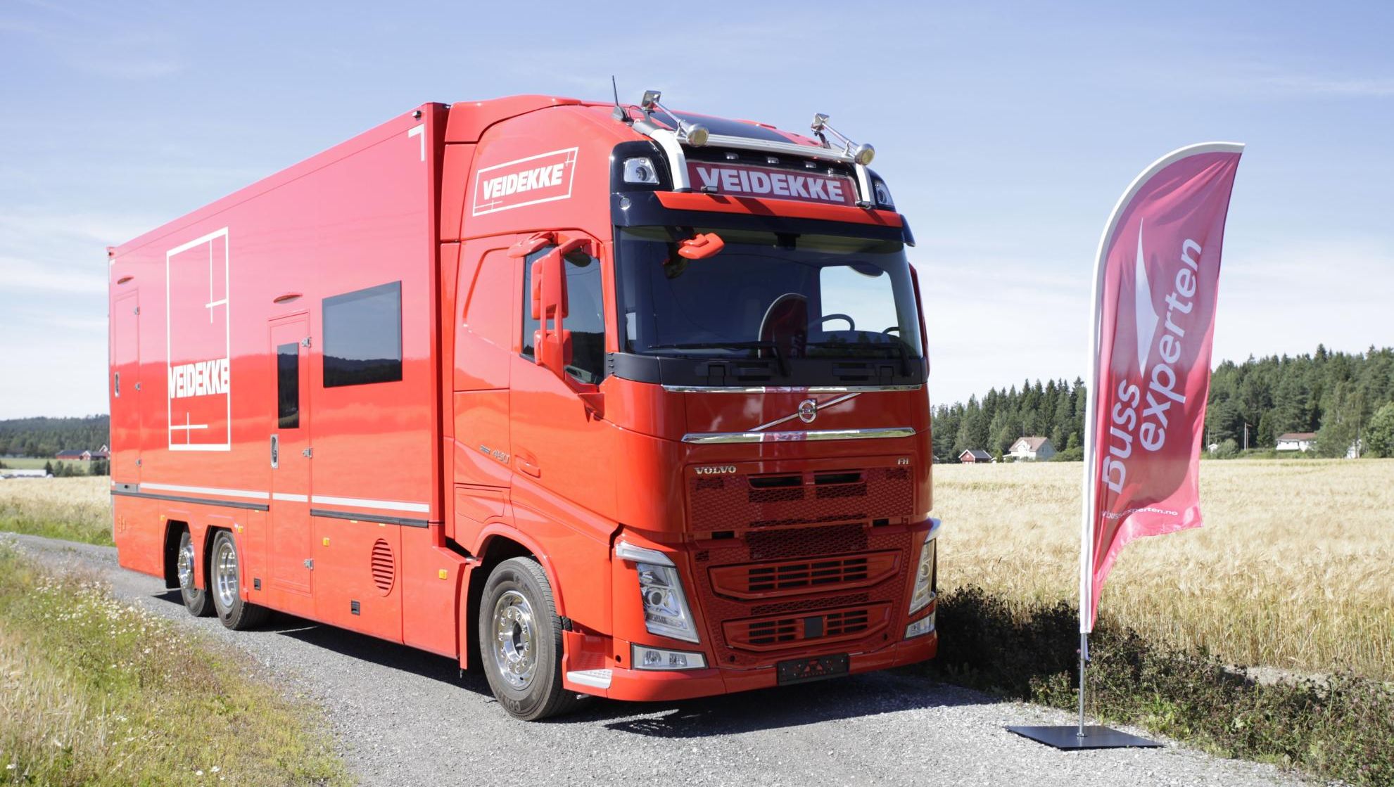 Rød ombygget lastebil for Veidekke på landevei