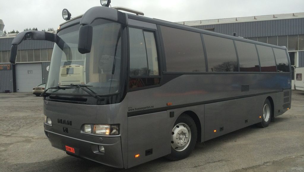 Grå MAN turbuss med sotede ruter sett skrått forfra fra høyre side.