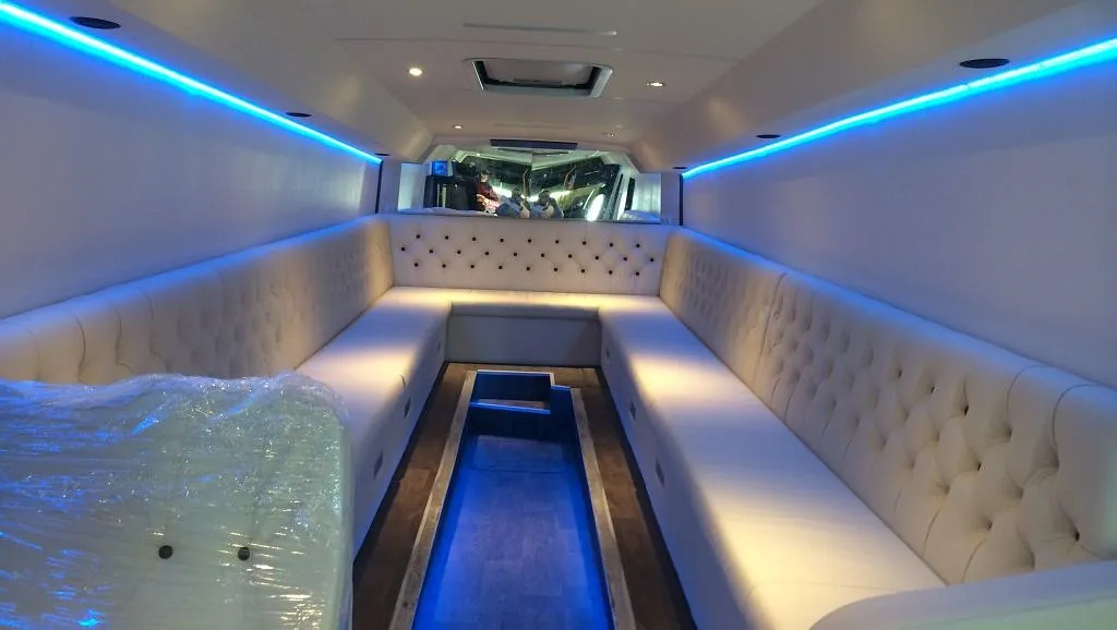 U-formet lounge i hvitt polstret skinn lyses opp av blått ledlys