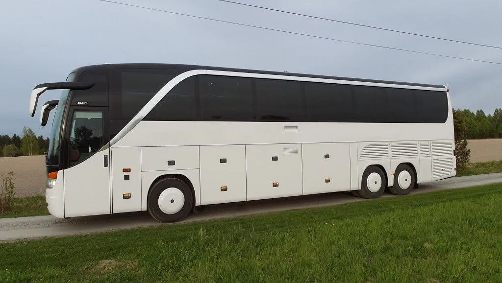 Hvit turbuss kjører langs landevei