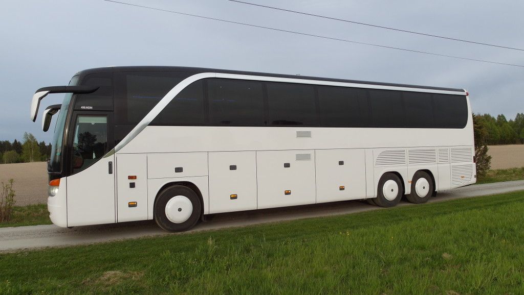 Hvit turbuss kjører langs landevei