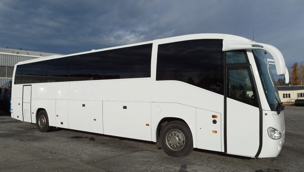 Hvit turbuss parkert på asfalt