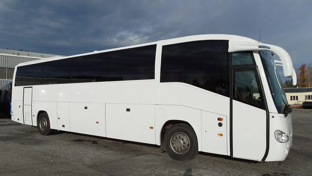 Hvit turbuss parkert på asfalt