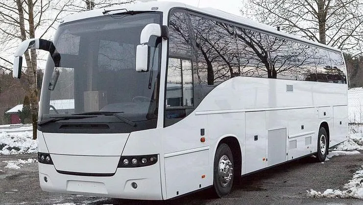 Hvit turbuss på grusvei i snølandskap