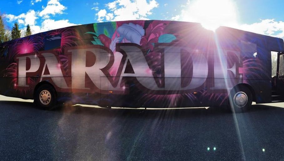 Svart buss i dagslys med teksten «PARADE» og fargerik dekor i bakgrunnen.