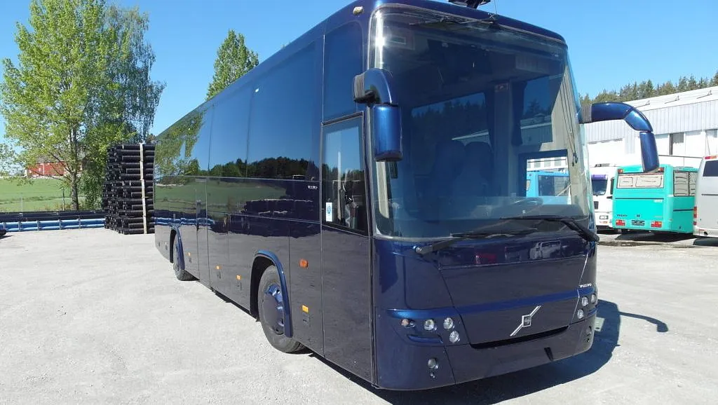 Mørkeblå buss med sotete ruter sett skrått fra front