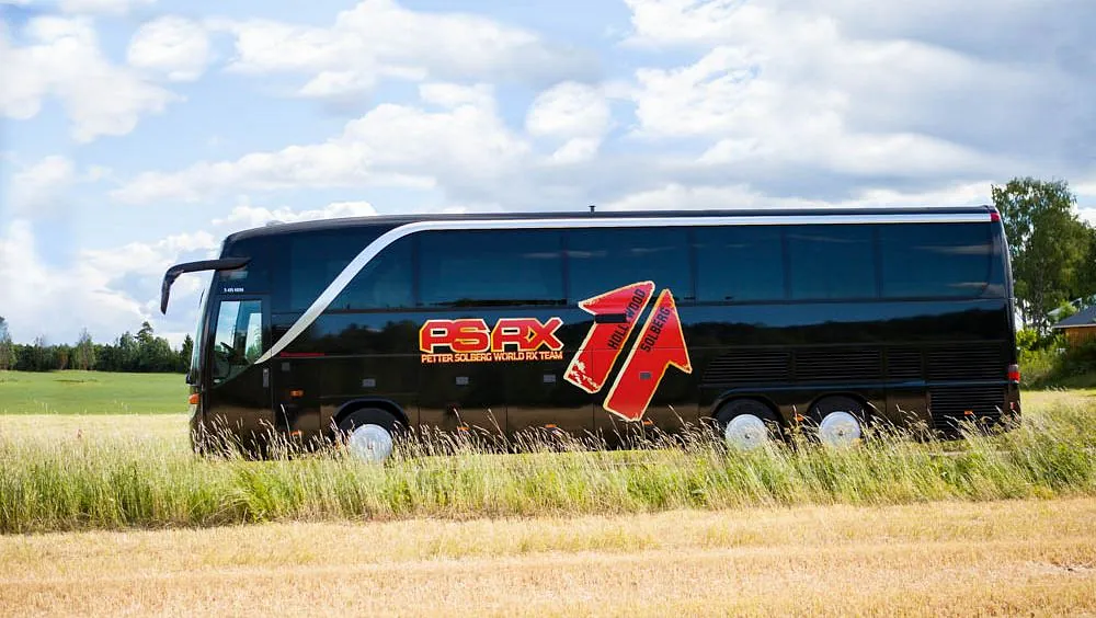 Svart turbuss fra siden mens den kjører på landevei